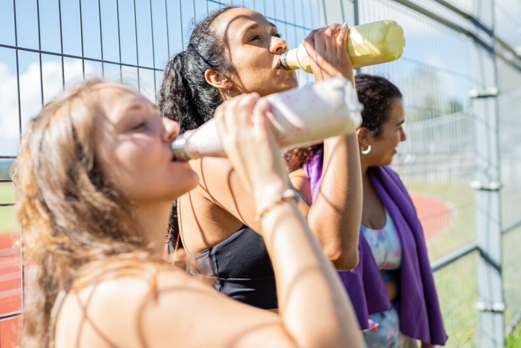 Women hydrating after exercise in South Florida heat - National Wellness Month